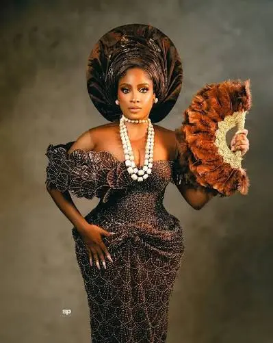 Bronze gele styled with a feather fan